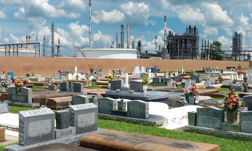 Cemetery in Cancer Alley, Louisiana, with refinery stacks in background