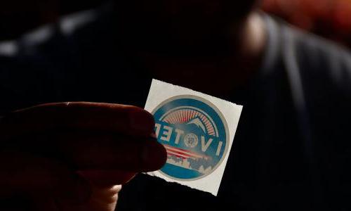 Person holding a sticker that reads "I voted."